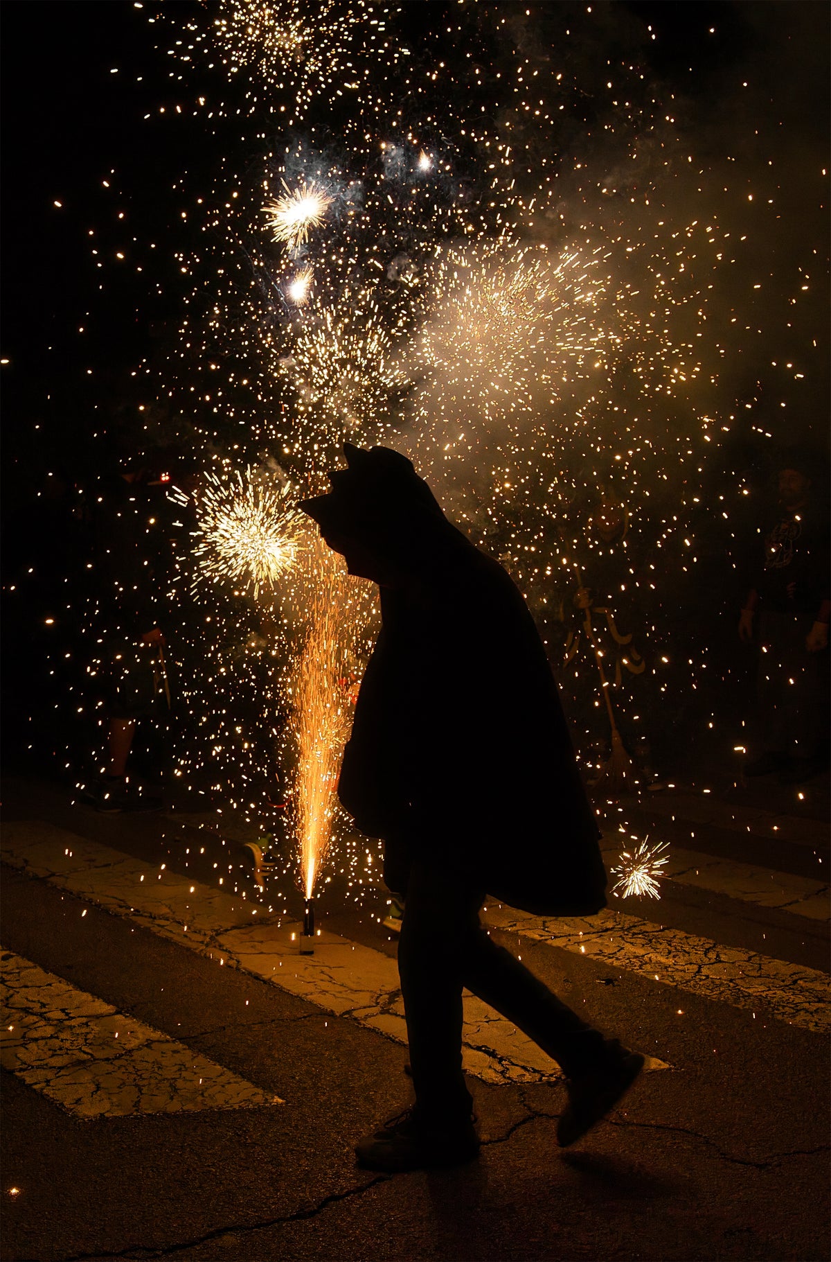 Figura encapuchada junto a una fuente de chispas en un correfoc de Mataró. Fotografía fine art, edición limitada de 5 ejemplares.