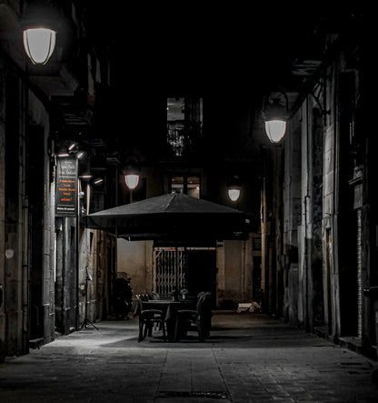 Empty terrace in a night alley of the Gothic Quarter, in black and white. Fine art photograph, limited edition of 5 copies.