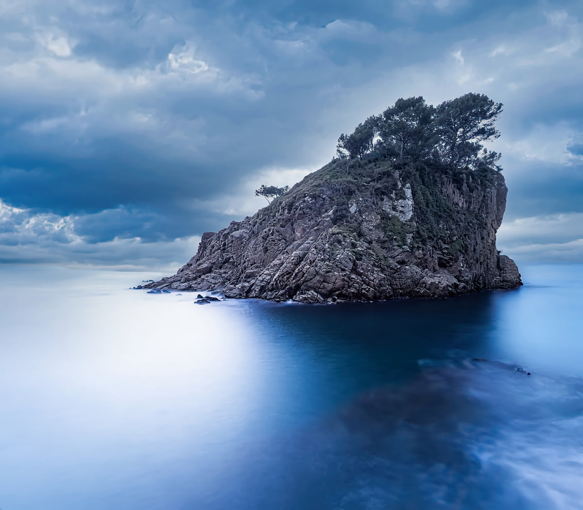 Islote rocoso con pinos frente a la Cala Sant Francés sobre un mar azul. Fotografía fine art, edición limitada de 5 ejemplares.